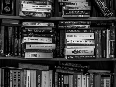 A black and white image of a packed bookshelf with various books in a library setting.