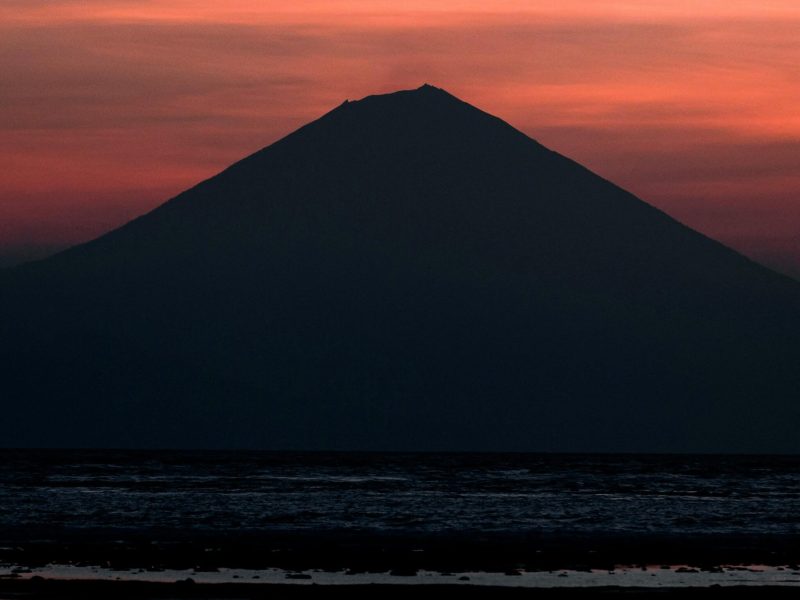 Captivating silhouette of Mount Rinjani against a vibrant sunset sky in West Nusa Tenggara, Indonesia.